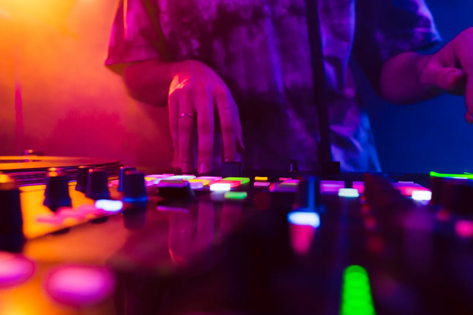 Primer plano de las manos de una DJ sobre la mesa de mezclas